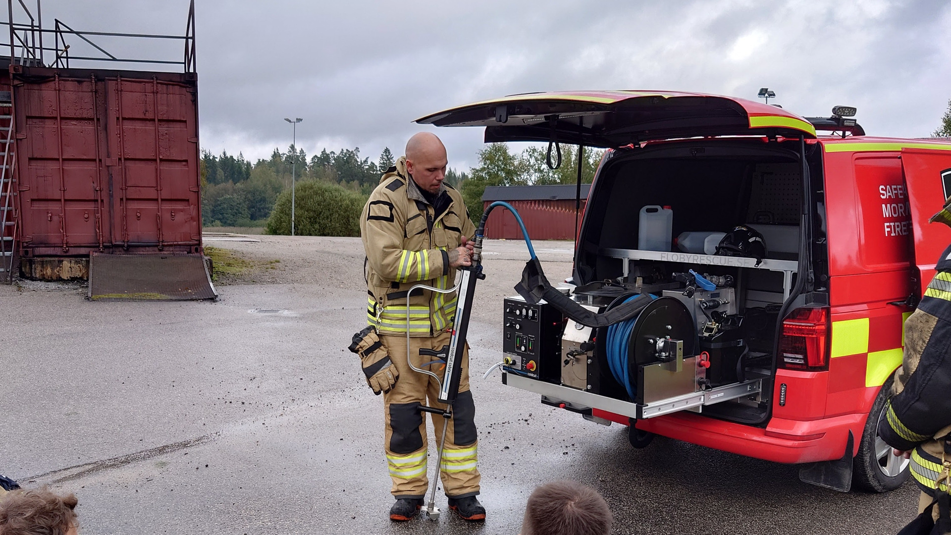 A group of firefighters sitting on the ground next to a fire truck